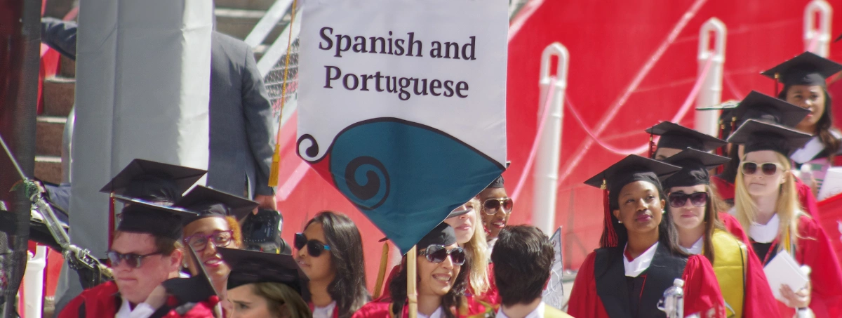 Graduates at Graduation holding spanish and portuguese department banner